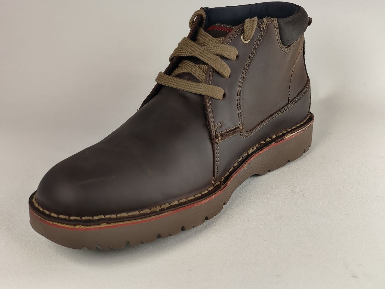 Brown leather boot with brown laces on a light gray background