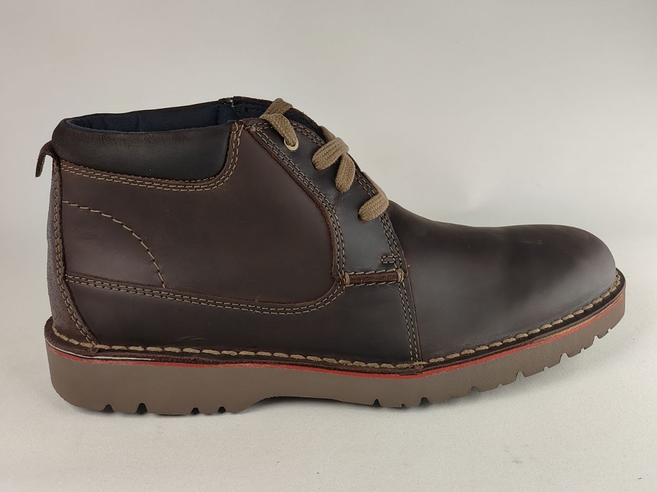 Brown leather boot with red sole on a light gray background