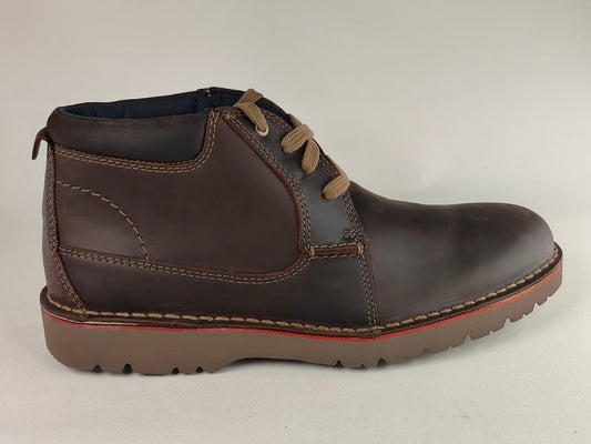 Brown leather boot with red sole on a light gray background