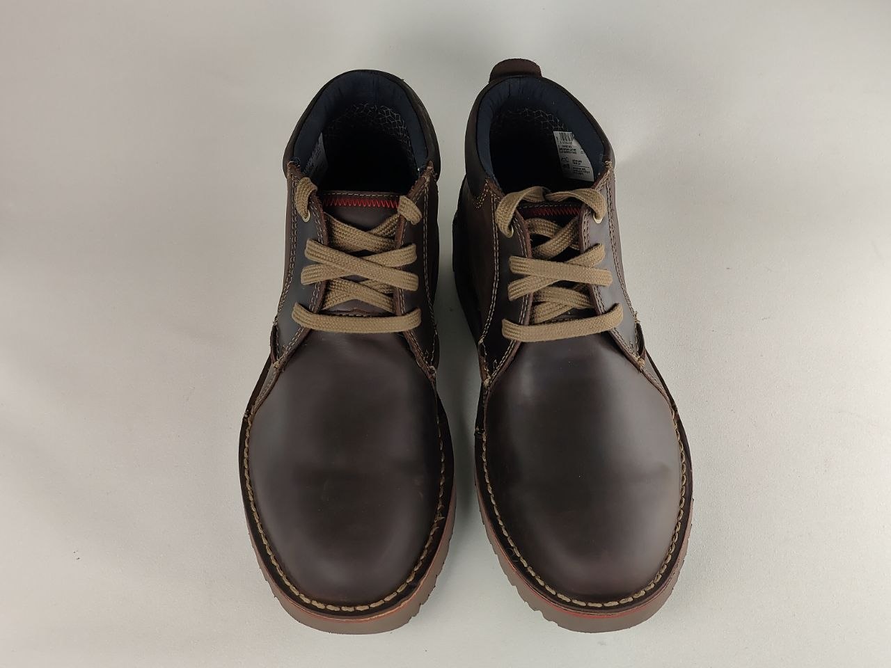 Pair of brown leather shoes with beige laces on a light gray background
