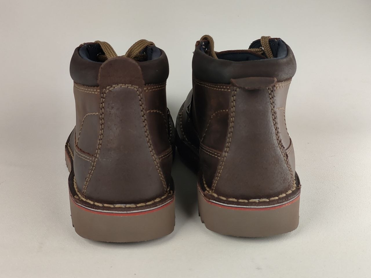 Pair of brown leather boots on a light gray background