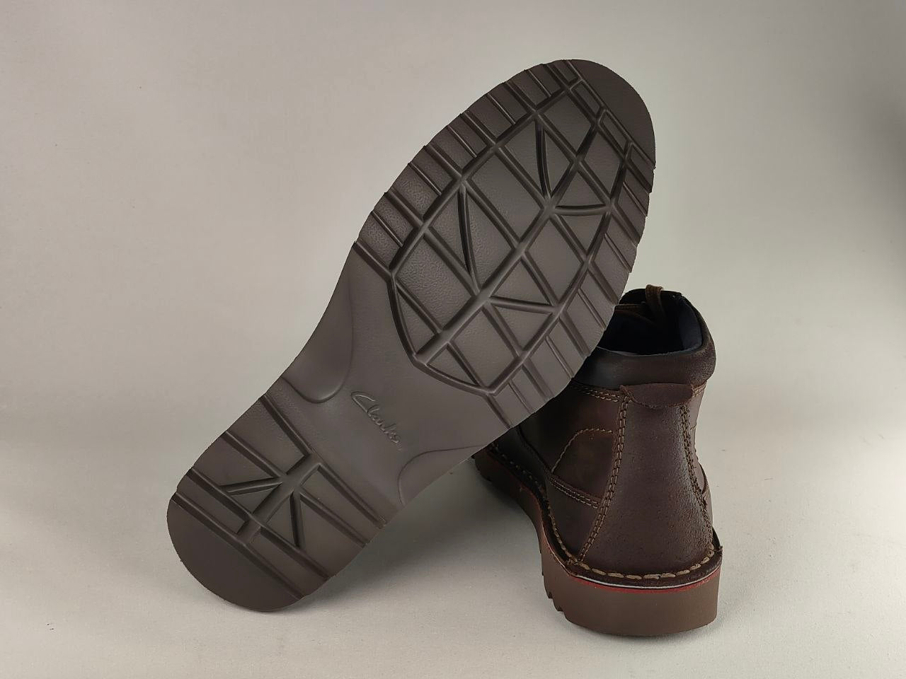 Brown leather boot with sole showing brand name on a light gray background