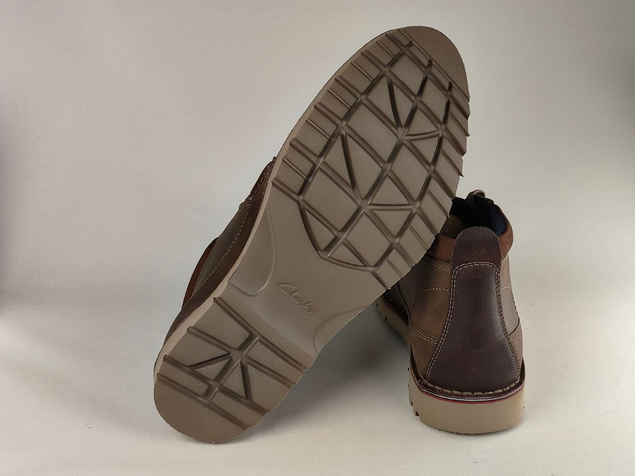 Brown leather boots with a focus on the sole on a light gray background
