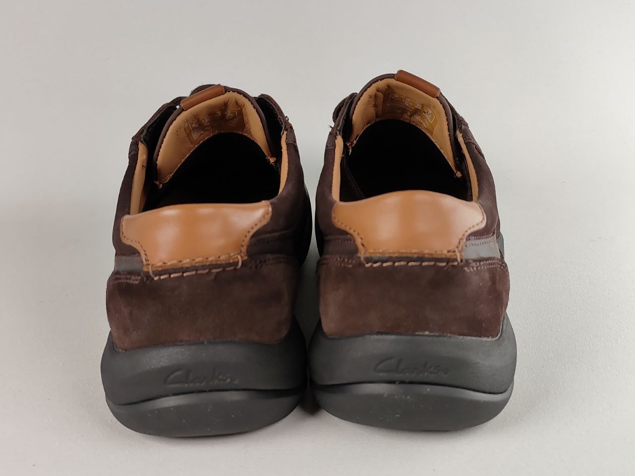Pair of brown leather shoes with tan accents on a light gray background