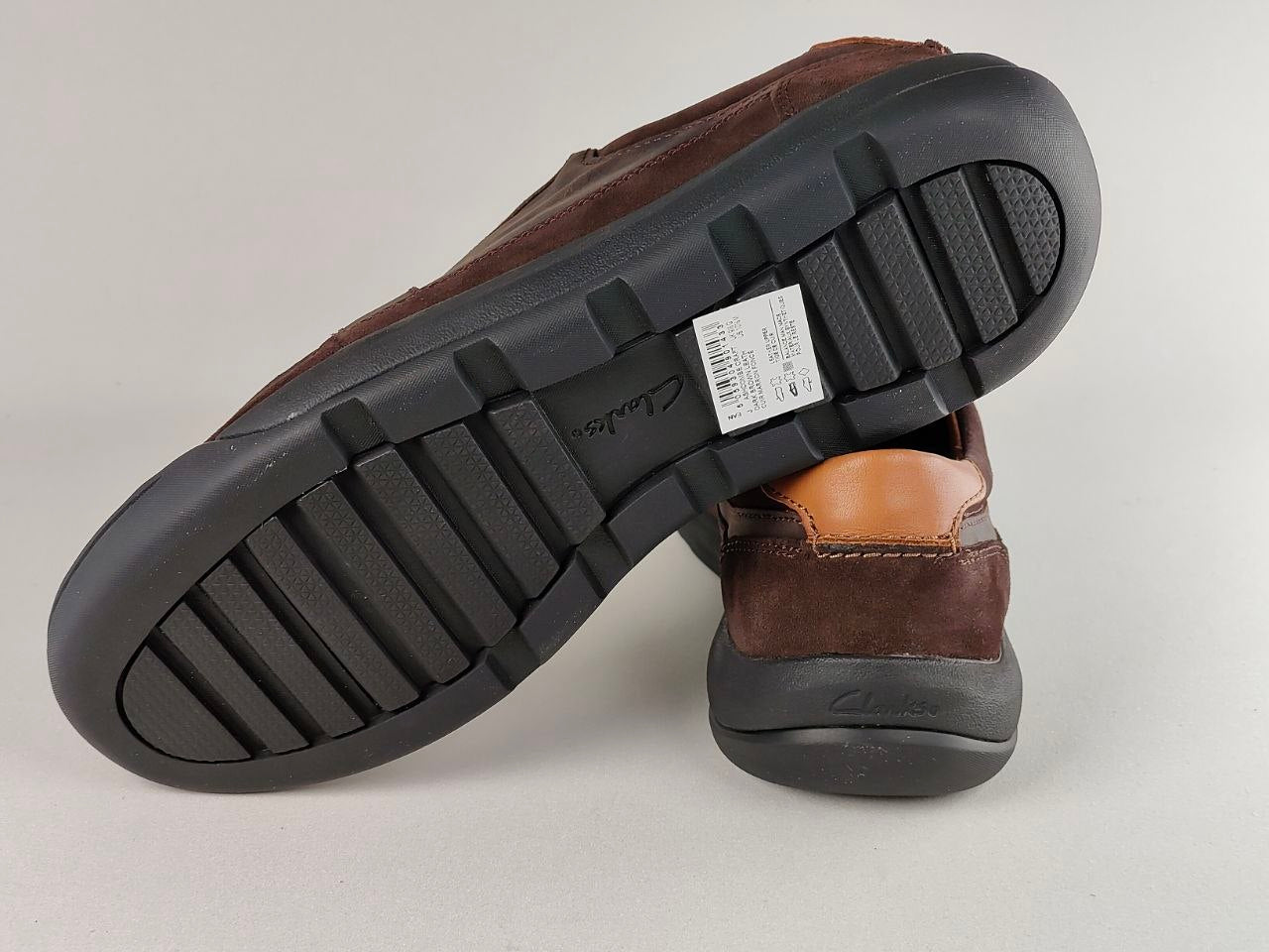 Brown shoe with black sole on a light gray background