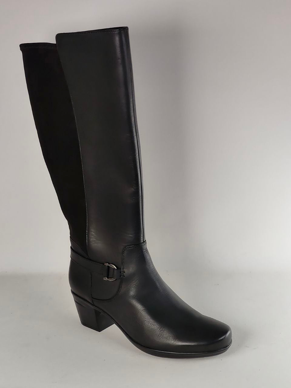 A single black knee-high leather boot with a low block heel and a decorative side buckle strap, photographed against a neutral light gray background.