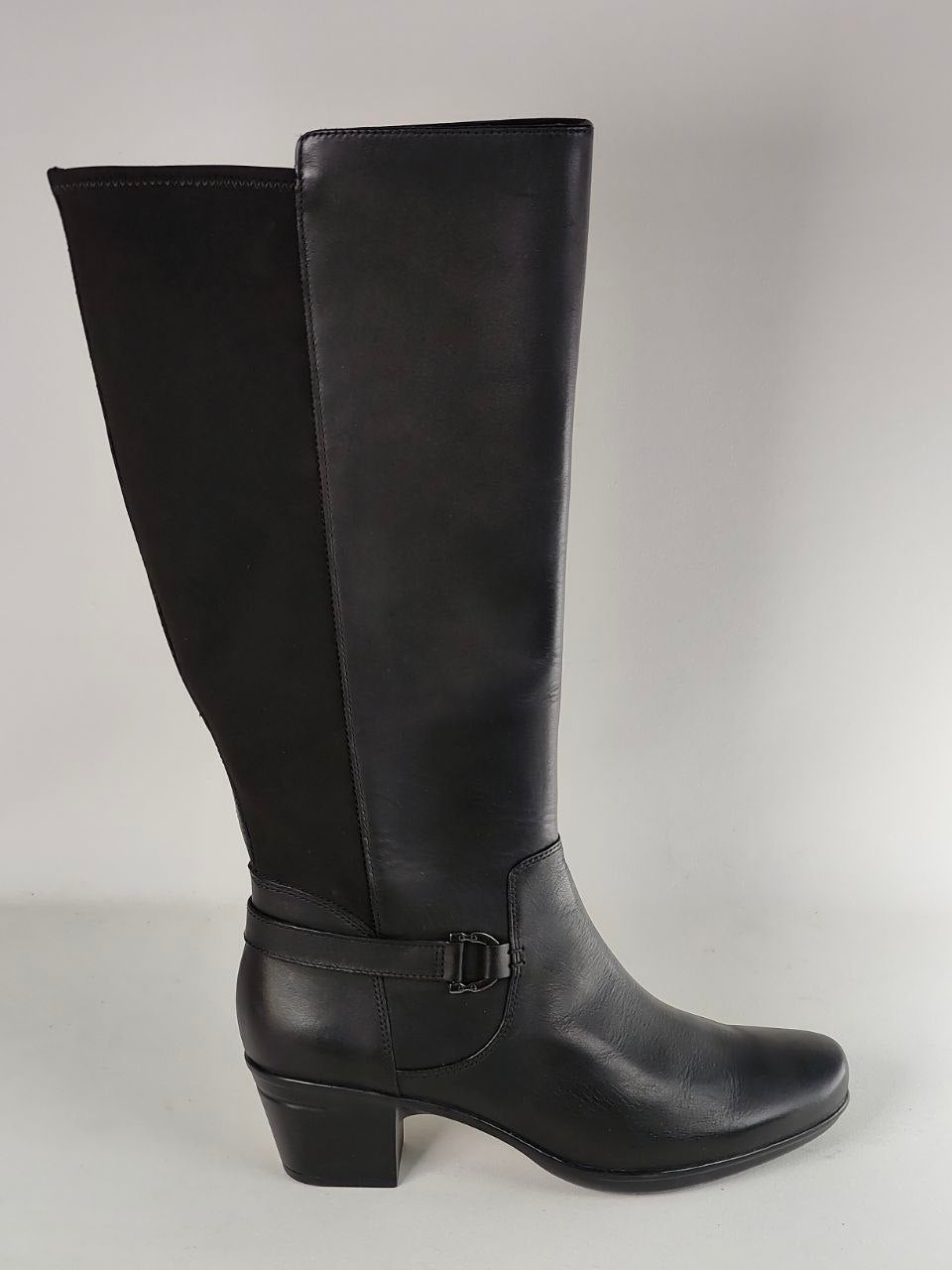 A single black knee-high boot with a block heel and ankle strap, photographed against a neutral light gray background.