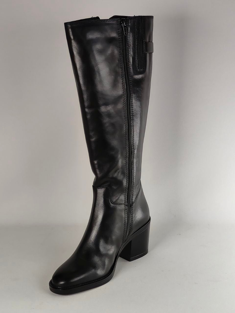 A single black leather knee-high boot with a block heel and side zipper, photographed against a neutral light gray background.