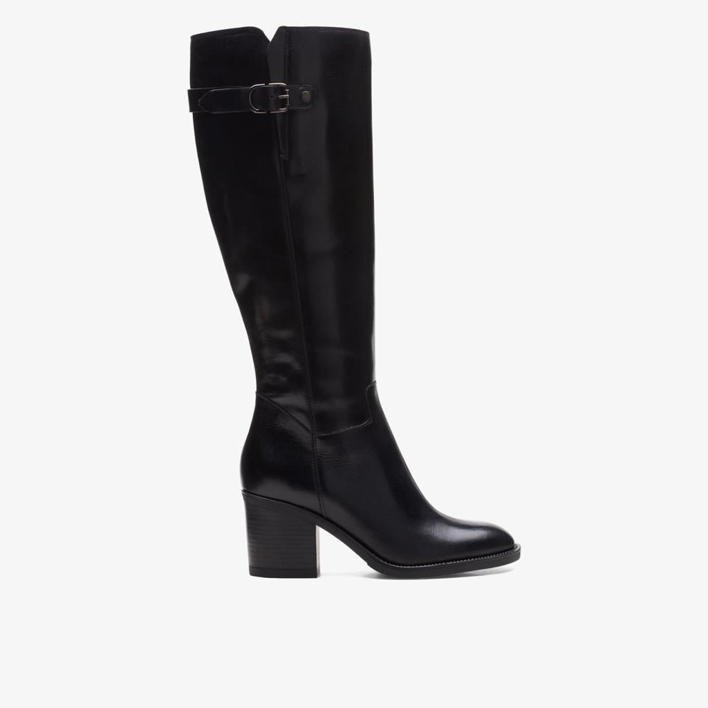 Black knee-high boot with a gold buckle on a light beige background