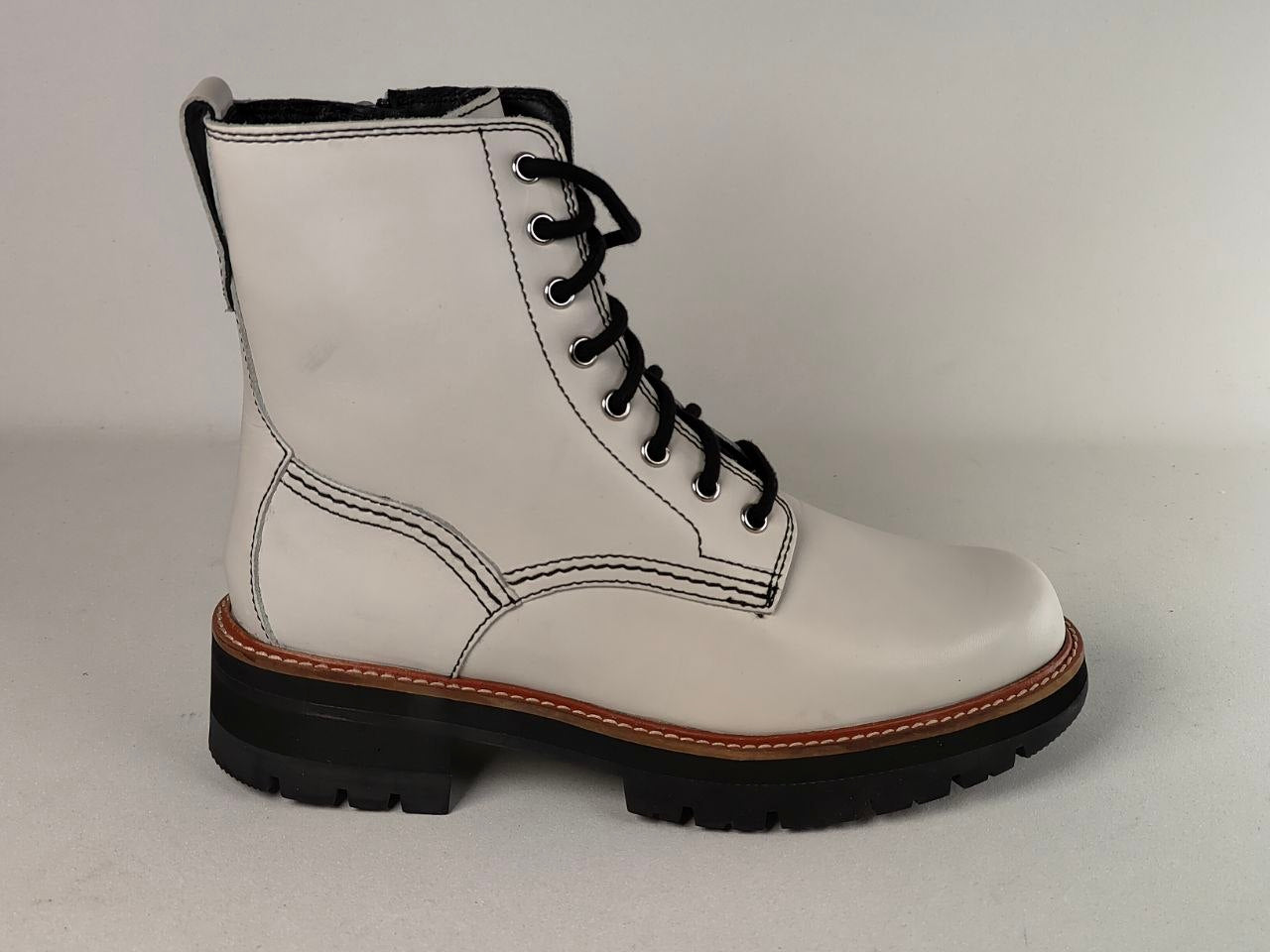 A white leather lace-up ankle boot with black laces, black sole, and a brown welt stripe, shown against a plain light gray background.