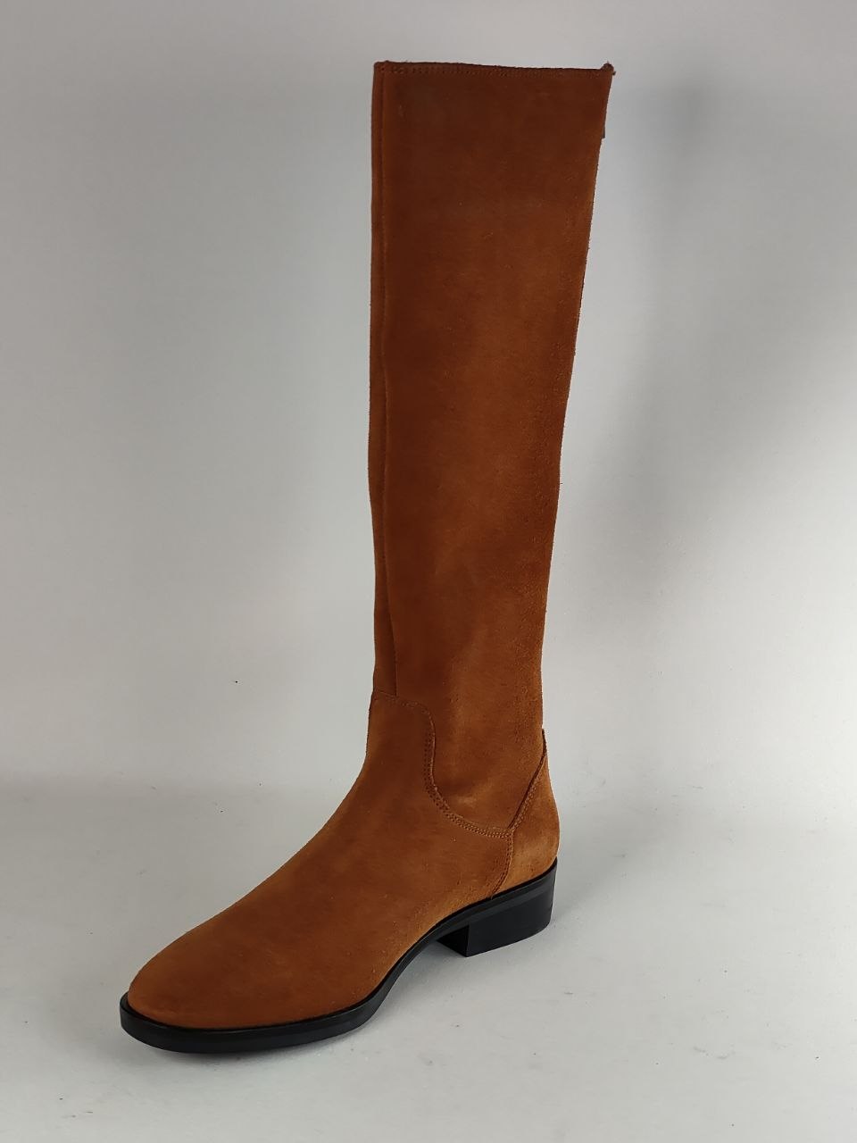 A single knee-high brown suede boot with a low black block heel and black sole, photographed against a neutral light gray background.