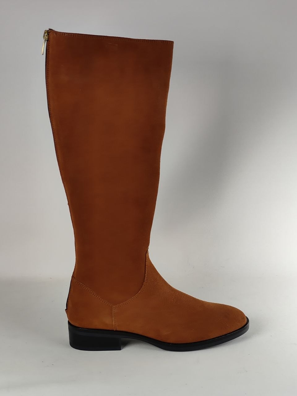 A tall brown suede knee-high boot with a low black block heel and side zipper, shown from a side profile against a neutral gray background.