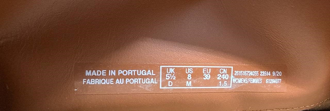 A close-up of a brown leather shoe interior showing a clear printed size and origin label that reads 'MADE IN PORTUGAL' with UK, US, EU, CN, D, M, and other sizing information.
