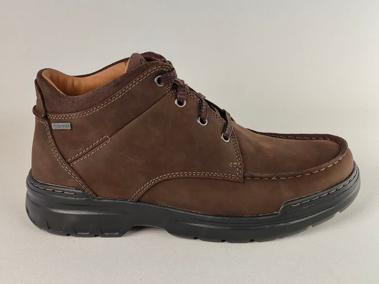 Brown leather boot with black sole on a light gray background