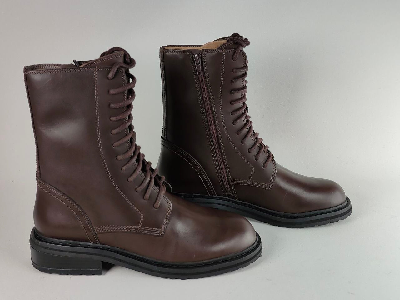 A pair of dark brown leather lace-up combat boots with side zippers and black soles, displayed on a light gray background.