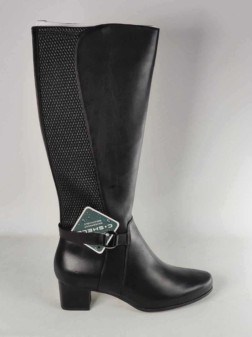 A single black knee-high boot with a textured mesh side panel, a low block heel, and a decorative buckle strap near the ankle, shown against a plain light gray background.