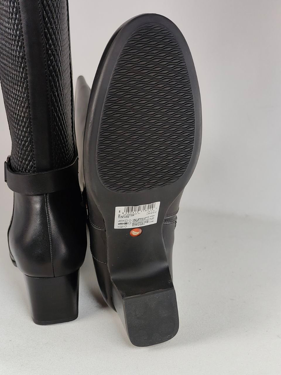 Black leather ankle boots shown from the side and sole, featuring a textured knit upper and a low block heel.