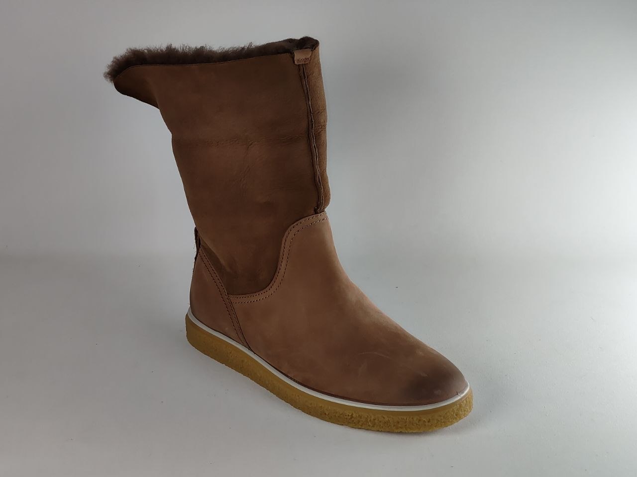 A brown suede mid-calf boot with a soft brown faux-fur trim at the collar and a tan rubber sole, shown against a neutral gray background.