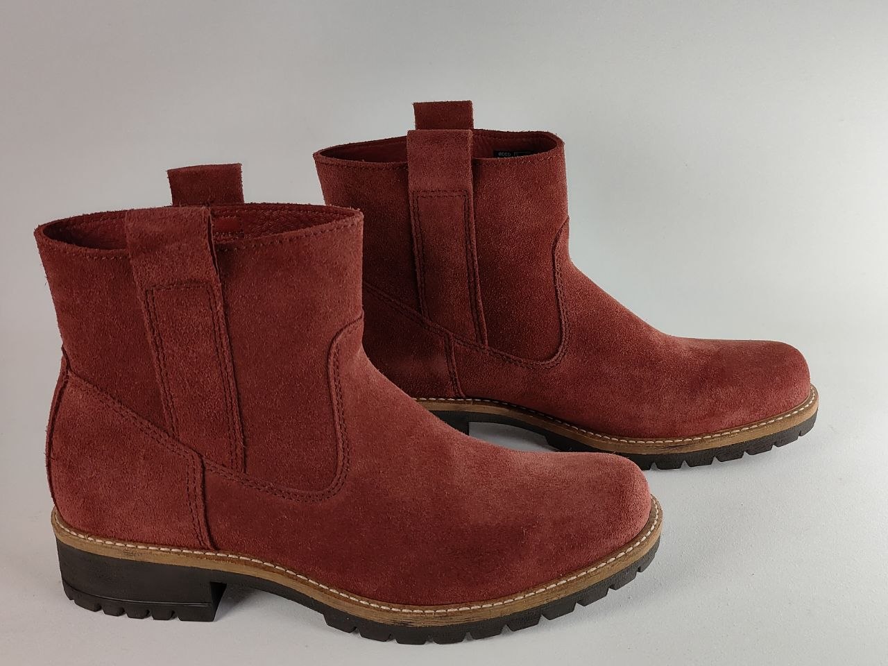 A pair of women's mid-calf suede boots in a deep burgundy red, featuring elastic side panels and pull tabs, set against a neutral gray background.