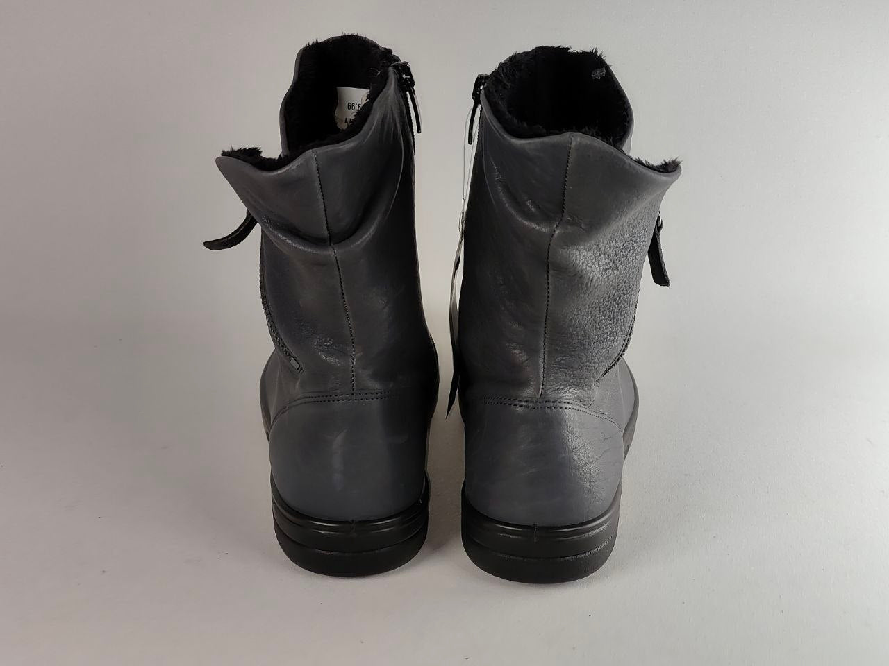 A pair of dark gray leather ankle boots with black soles and a black faux-fur lining, shown from the back against a light gray background.