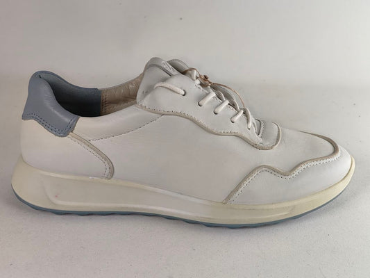 A white leather low-top sneaker with a gray heel tab and a thick cream-colored sole, shown from a side profile view against a neutral light gray background.