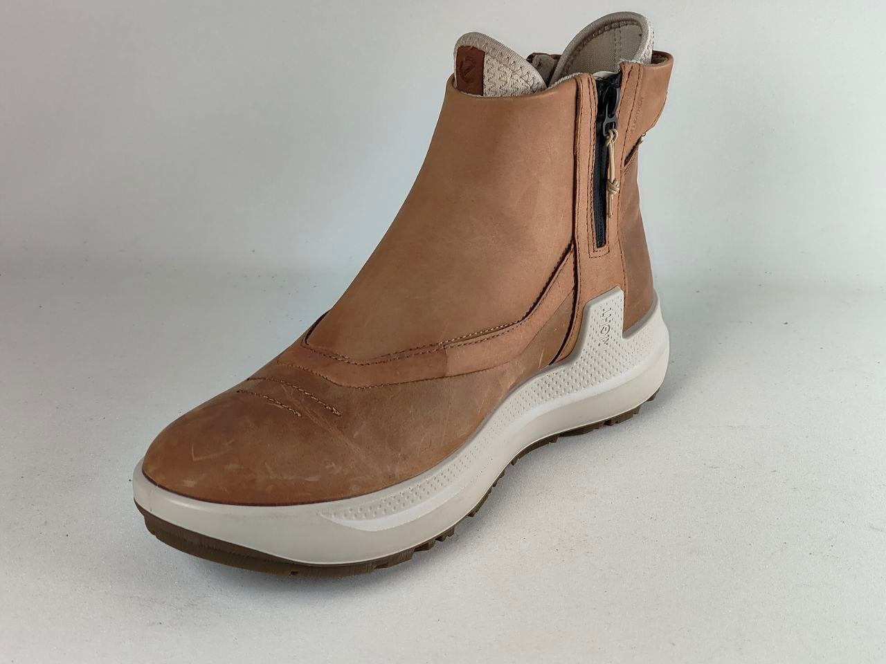 A single brown suede ankle boot with a side zipper, a thick white midsole, and a textured brown outsole, shown against a plain light gray background.
