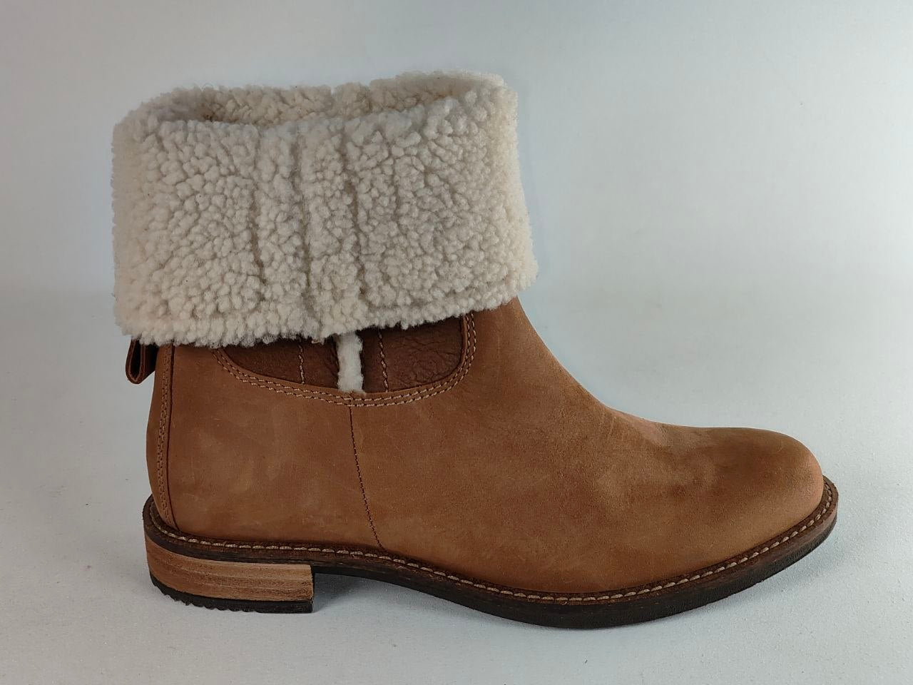 A brown suede ankle boot with a thick, fluffy cream-colored shearling-style cuff, shown from a side profile against a light gray background.