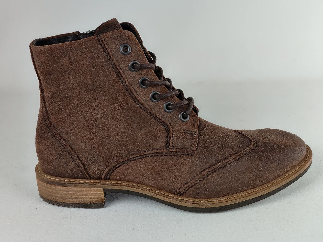 A brown suede lace-up ankle boot with a low stacked heel and tan sole, shown from a side profile on a light gray background.