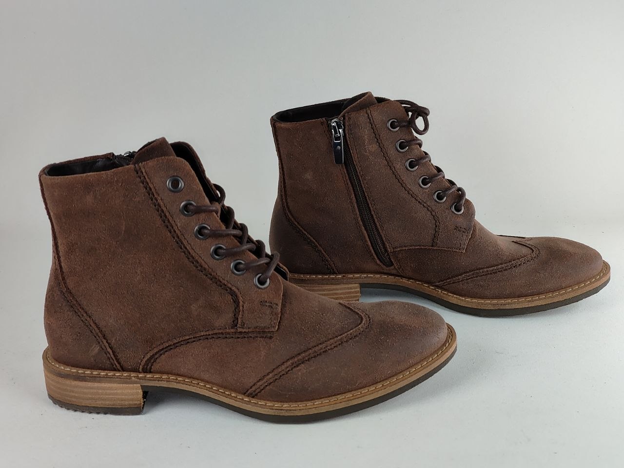 A pair of dark brown suede lace-up ankle boots with side zippers, shown on a light gray background.