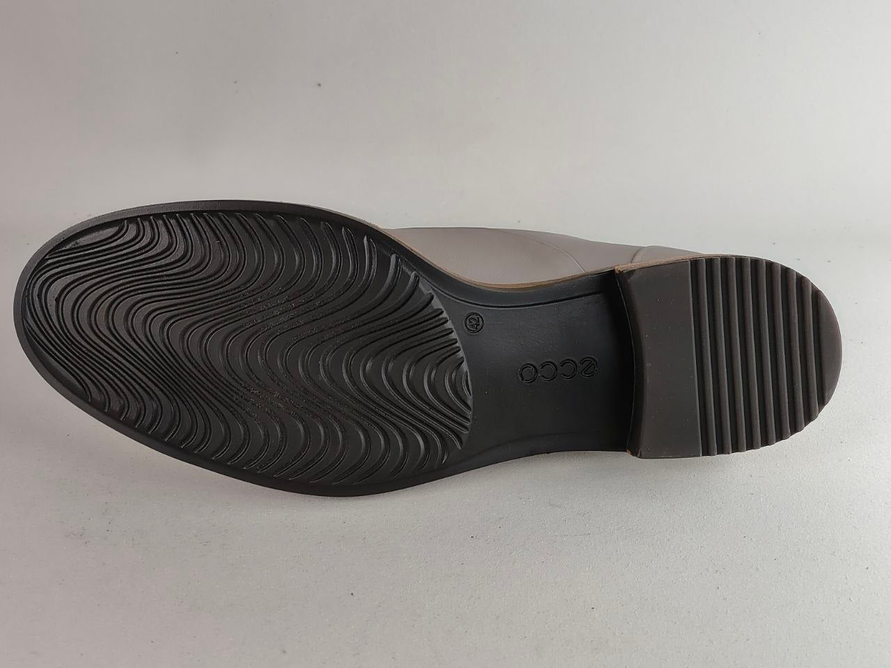 The black rubber outsole of a shoe, showing the tread pattern and embossed 'ecco' brand name, photographed against a light gray background.