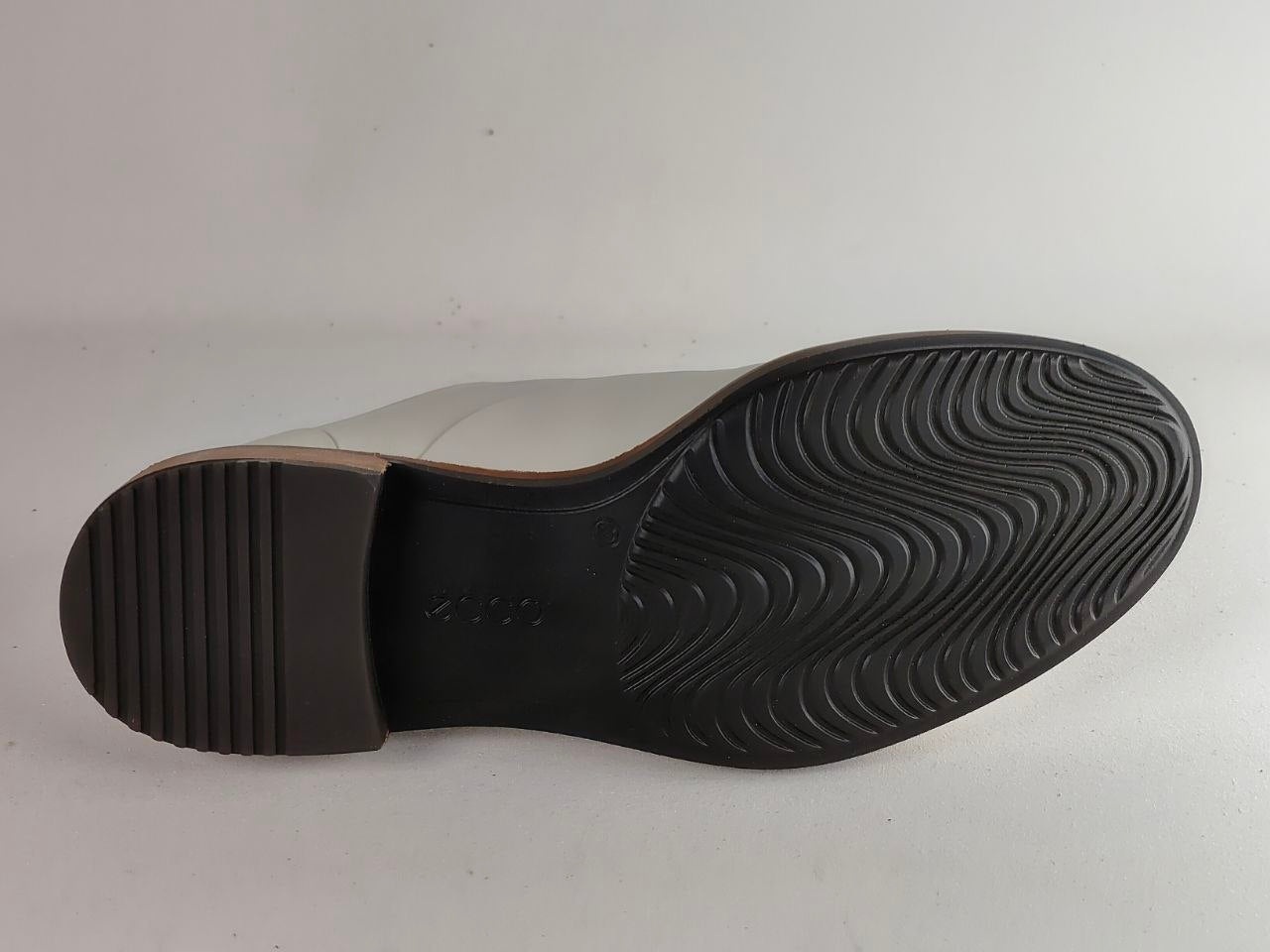 The outsole of a light gray boot, showing a black treaded rubber bottom with a textured heel and a wavy tread pattern on the front.