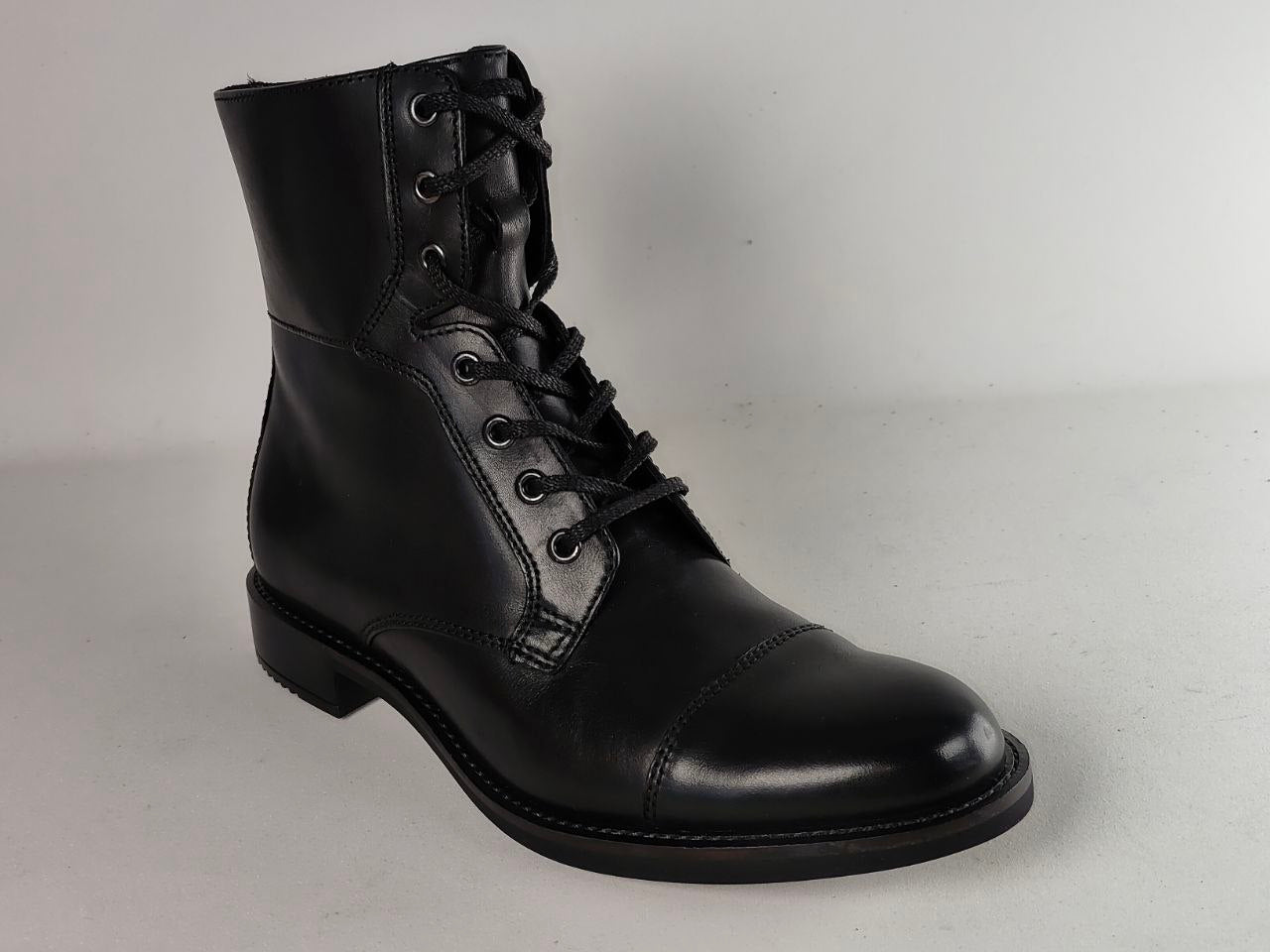 A single black leather lace-up ankle boot with a rounded toe and low block heel, photographed on a light gray studio background.
