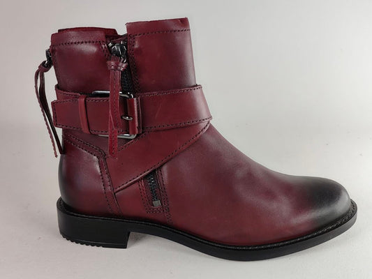 A burgundy leather ankle boot with a side zipper, a decorative buckle strap, and a low black block heel, shown against a plain light gray background.