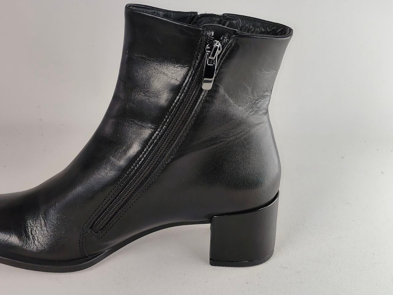 A black leather ankle boot with a side zipper, low block heel, and silver zipper pull, shown against a plain light gray background.