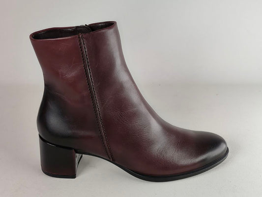 A dark burgundy leather ankle boot with a low block heel, shown from a side profile against a neutral light gray background.