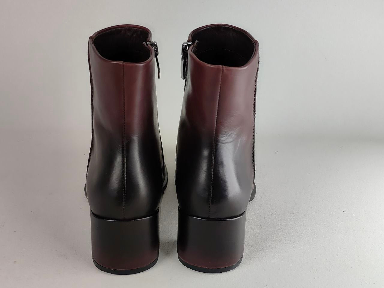 A pair of women's ankle boots in dark burgundy leather, shown from the back on a light gray background.