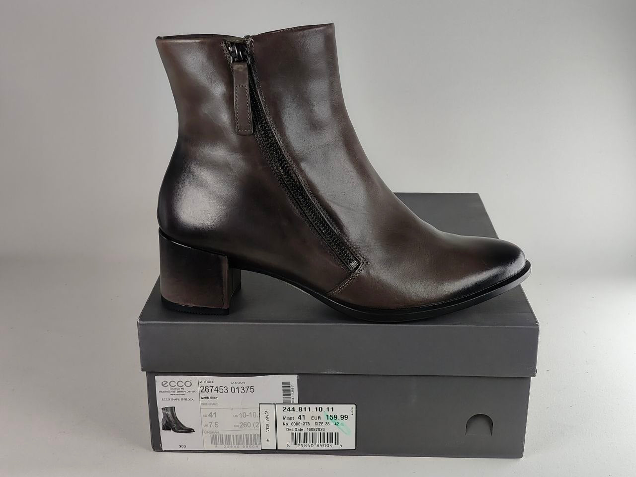 A dark brown leather ankle boot with a side zipper and block heel, displayed on top of its gray ECCO shoebox against a neutral gray background.