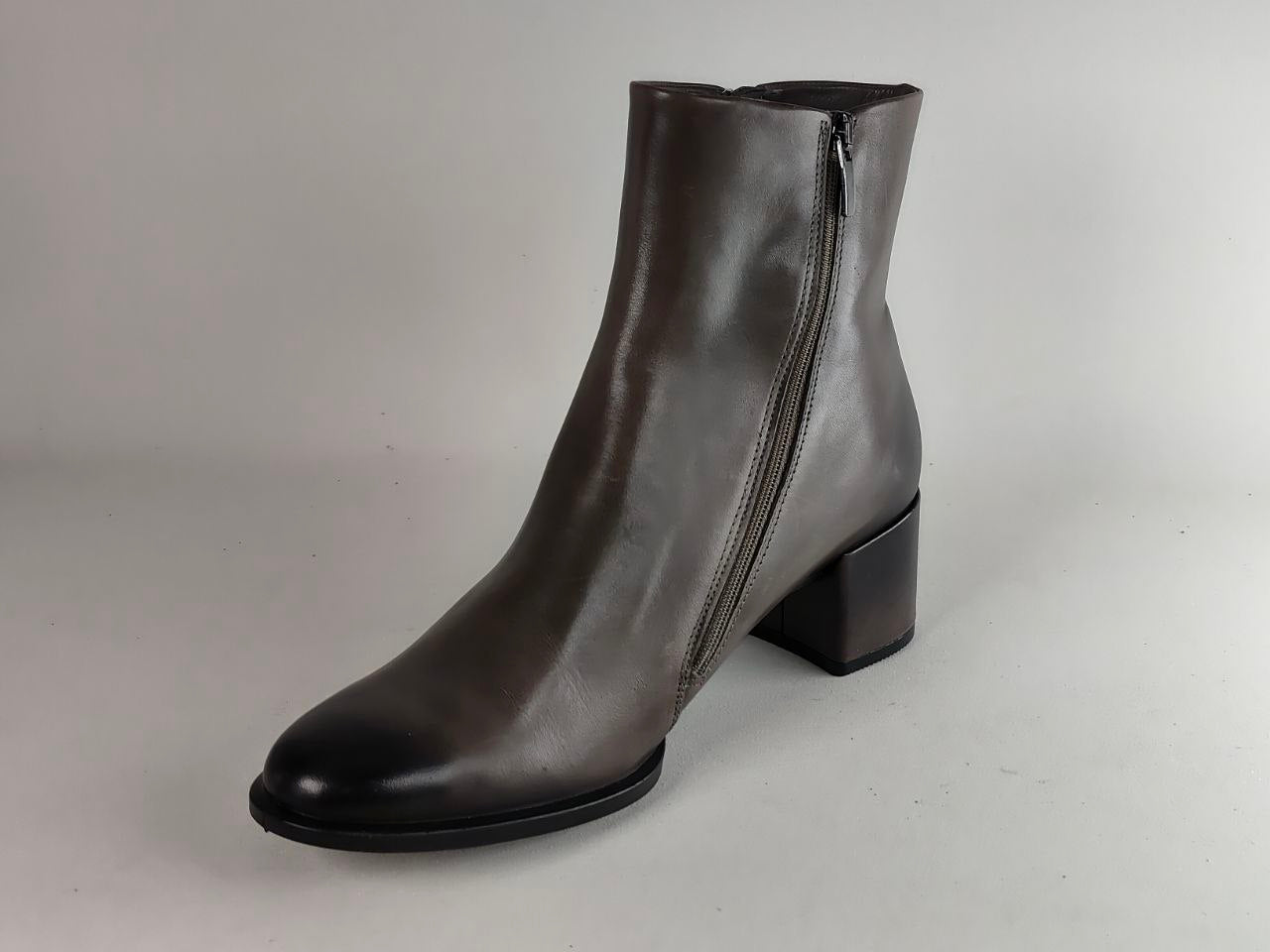 A dark gray leather ankle boot with a low block heel and a side zipper, photographed on a neutral light gray background.