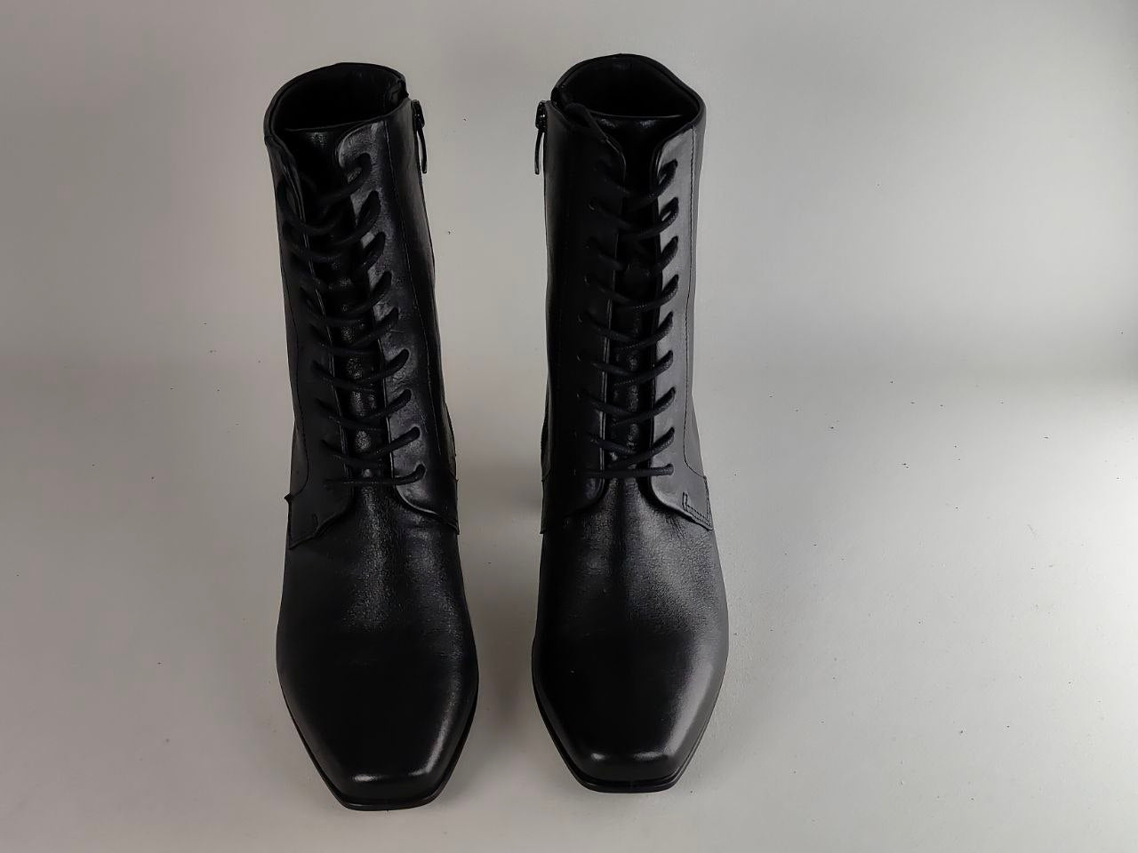 A pair of black leather lace-up ankle boots with side zippers, shown against a neutral light gray background.