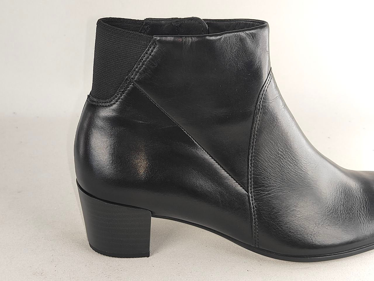 A black leather ankle boot with a low block heel and elastic side gore, shown from a side profile view against a light gray background.