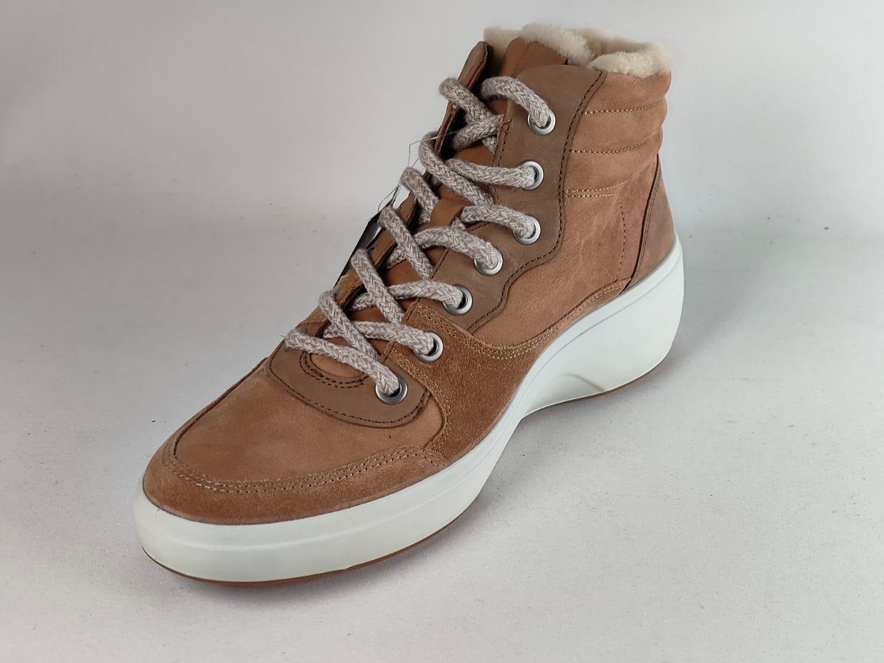A brown suede high-top sneaker boot with a white sole and fluffy white lining, shown on a neutral light gray background.