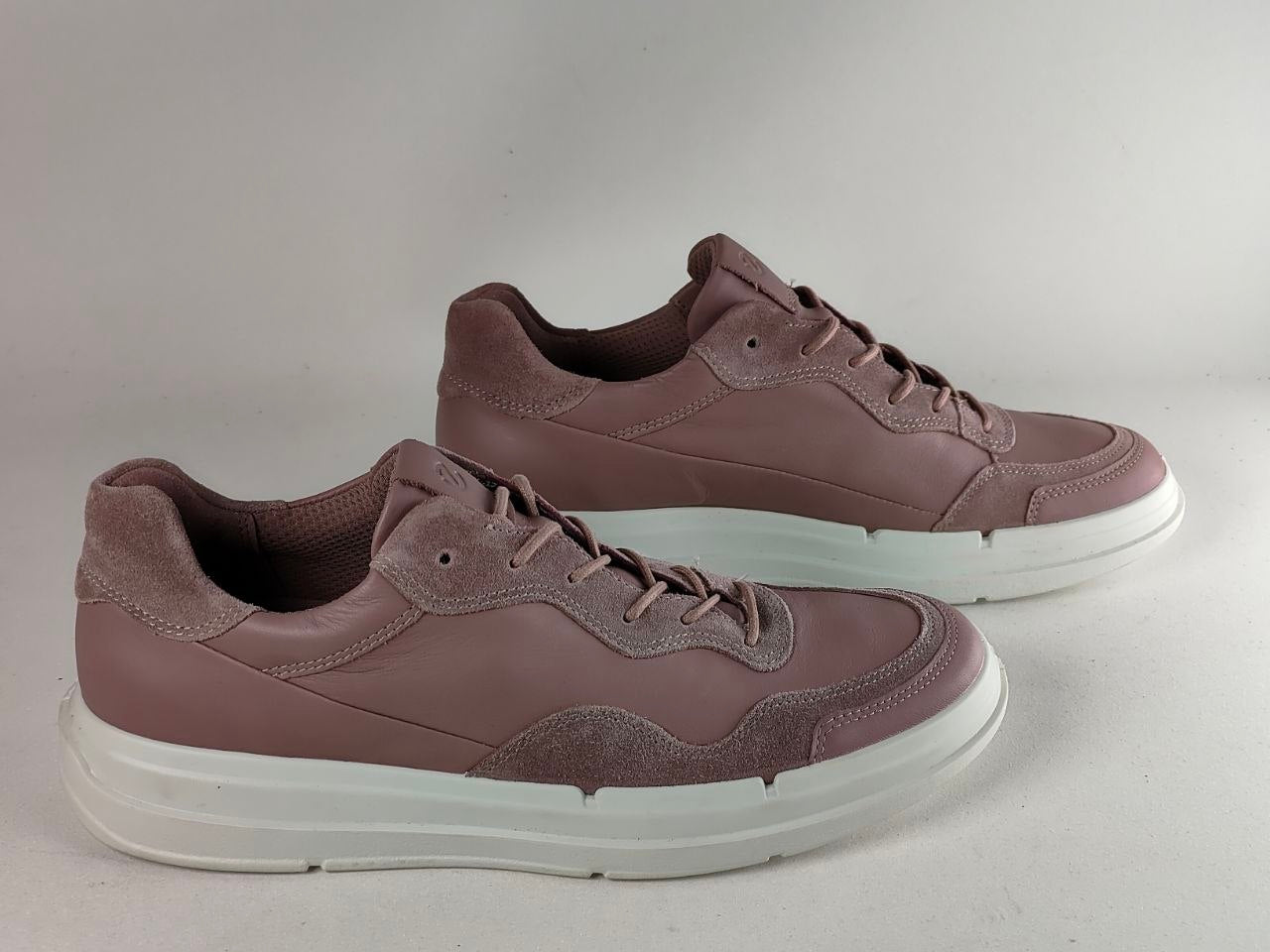 A pair of low-top sneakers in a dusty mauve-brown color with white platform soles, photographed on a neutral light gray background.