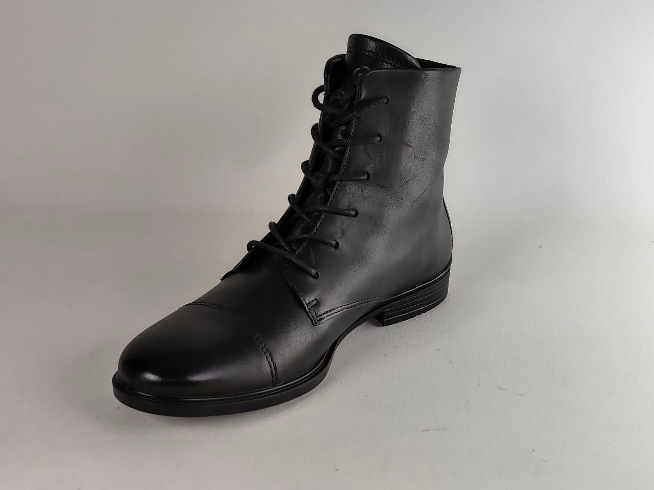 A single black leather lace-up ankle boot with a rounded toe and low stacked heel, photographed on a light gray studio background.