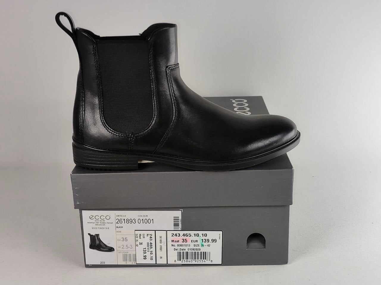 A black leather Chelsea boot with elastic side panels, shown resting on top of its gray ECCO shoebox against a light gray background.