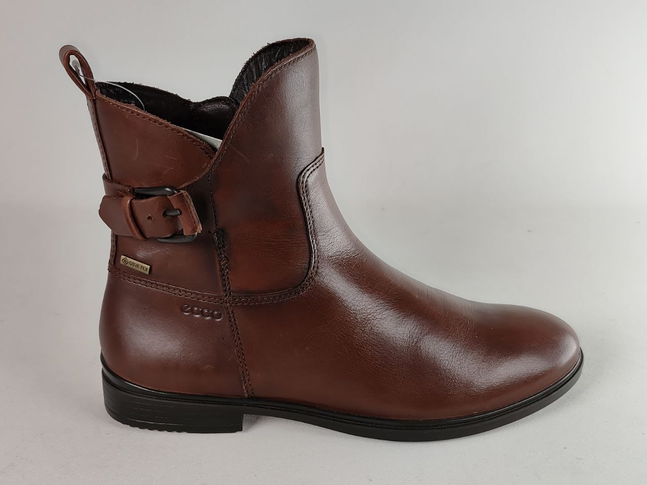 A brown leather ankle boot with a side buckle strap, shown from a side profile against a light gray background.