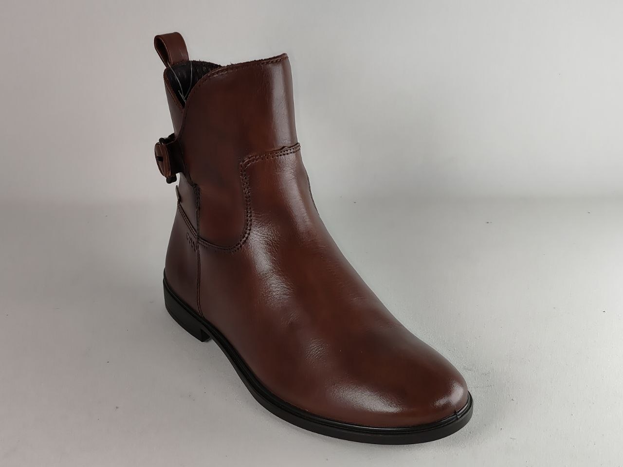 A single brown leather ankle boot with a side pull tab and elastic side gore, photographed on a neutral light gray background.