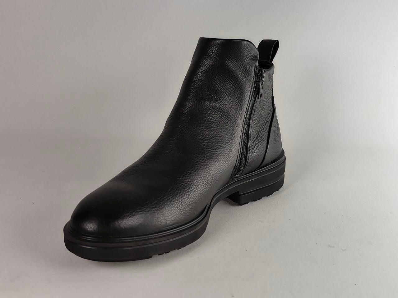 A single black leather ankle boot with a side zipper, shown from a three-quarters angle against a neutral gray background.