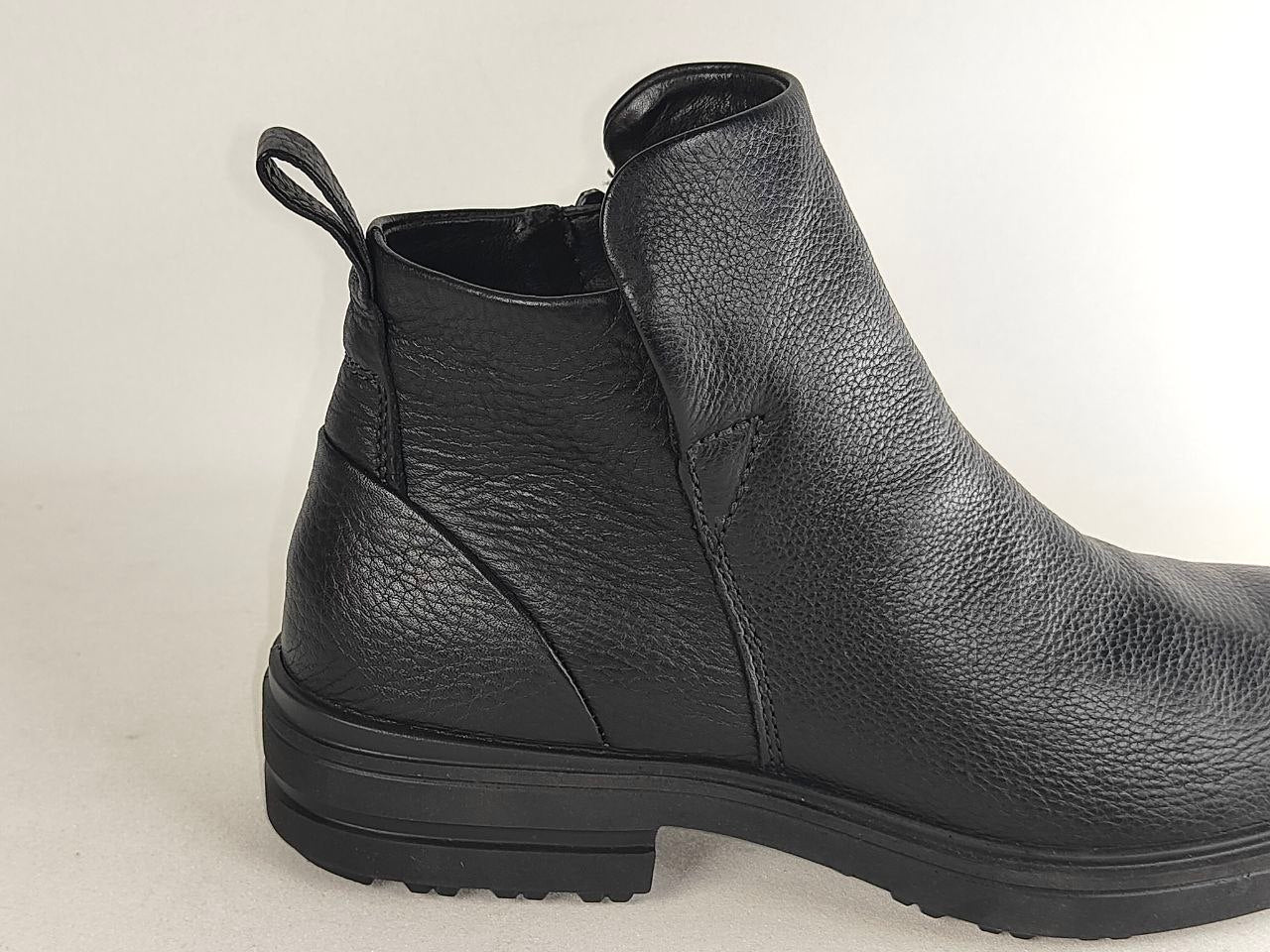 A black pebbled leather ankle boot with a side pull tab and a low block heel, shown from a side profile view against a light gray background.