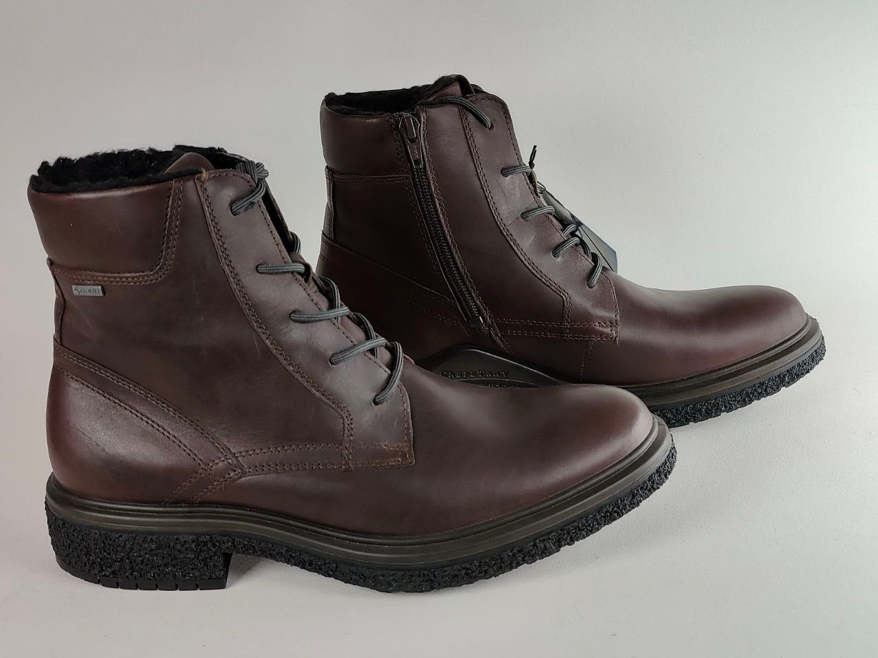 A pair of dark brown leather lace-up ankle boots with black soles and a black fleece lining, displayed on a light gray background.
