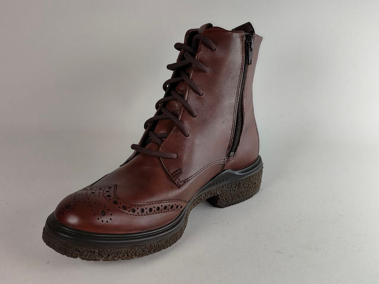 A dark brown leather lace-up ankle boot with a side zipper, brogue detailing on the toe, and a chunky dark sole, shown against a neutral light gray background.